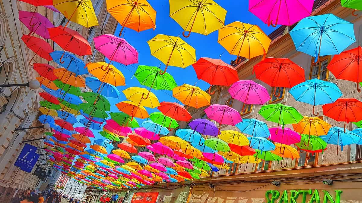 Stradă decorată cu umbrele colorate suspendate.